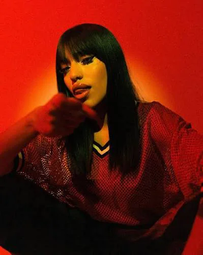 FLVCKKA seated in red light wearing a red mesh top.